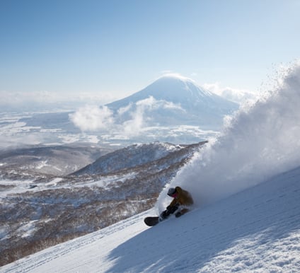 A rider surfing deep powder down a slope in Japan