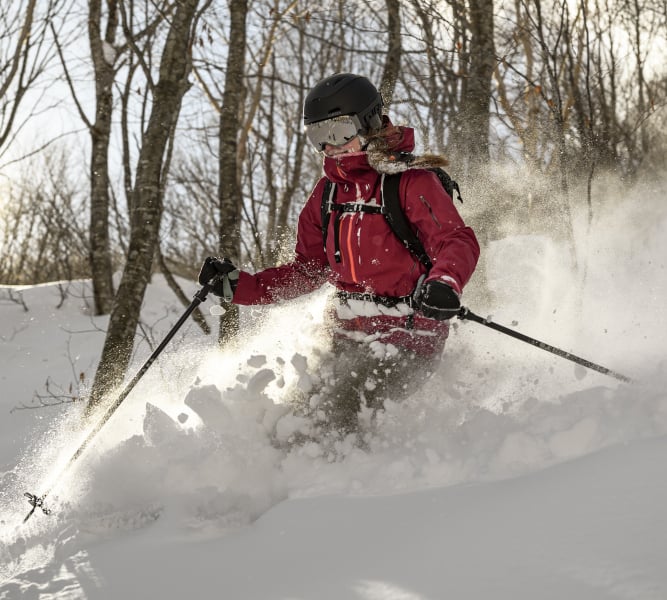 A woman skiing through deep snow in a forest