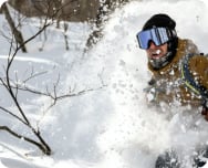 A snowboarder with a large cloud of powder behind them