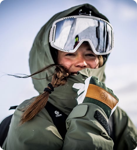 A woman wearing gear for a day out on the slopes smiling at the camera
