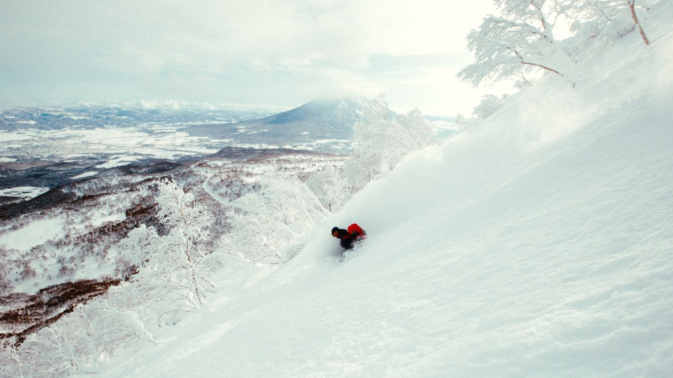 A rider surfing deep powder down a slope in Japan
